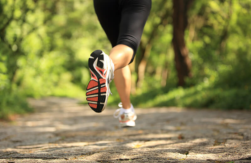 woman running through a park, wearing running shoes