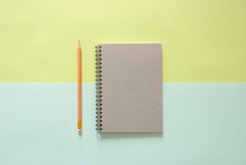 notebook and pencil on a coloured background