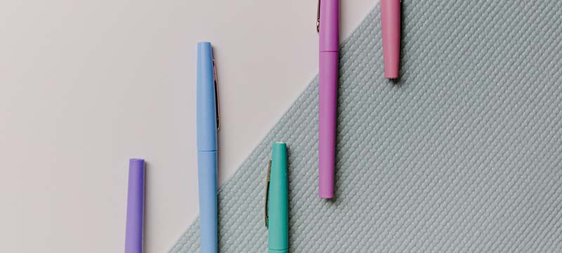 different coloured pens laid out on a table